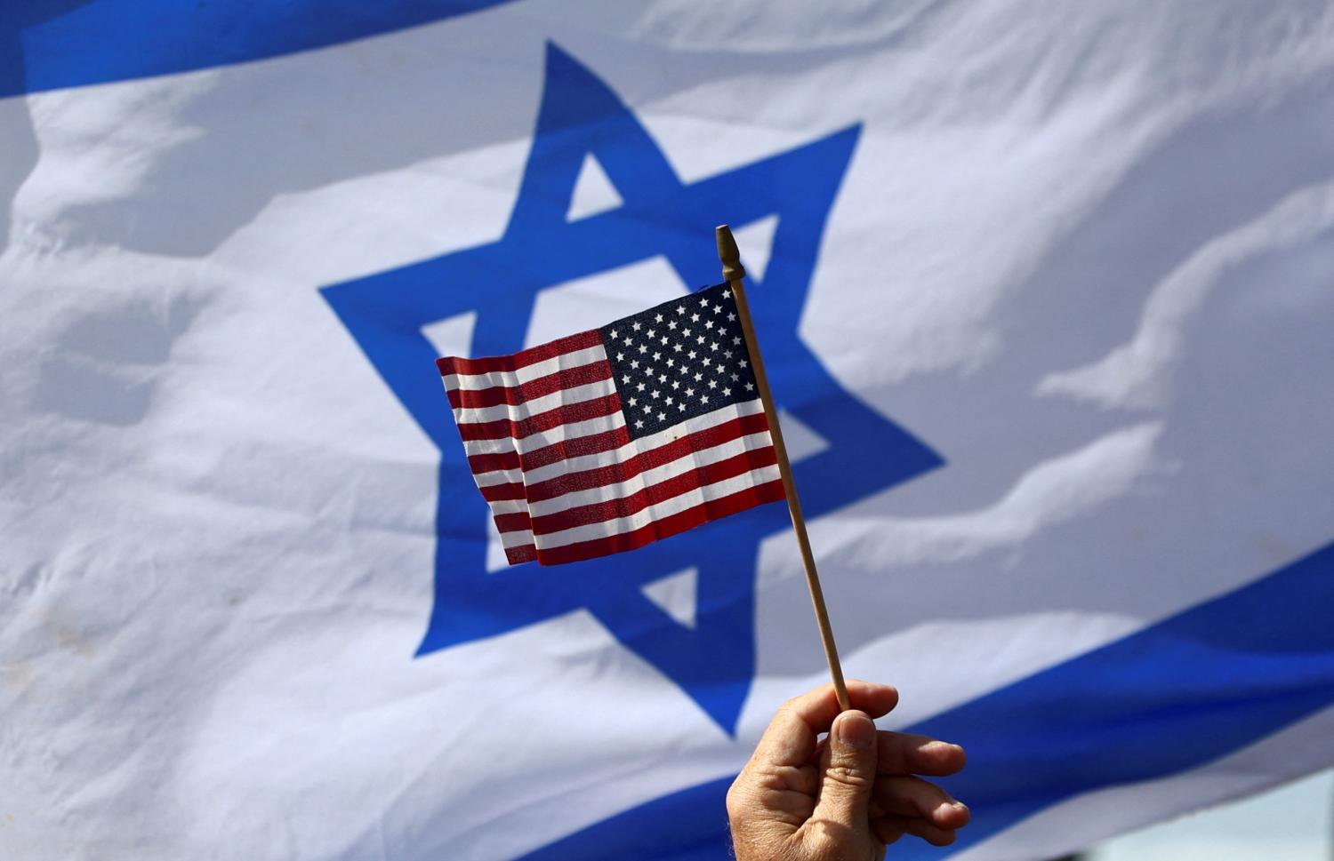 A view of a U.S. flag and an Israeli flag held up by people during a demonstration to show support for U.S. President Joe Biden, for not inviting Israeli Prime Minister Benjamin Netanyahu to the White House, in front of the U.S. Consulate in Tel Aviv, Israel, March 30, 2023. REUTERS/Ronen Zvulun
