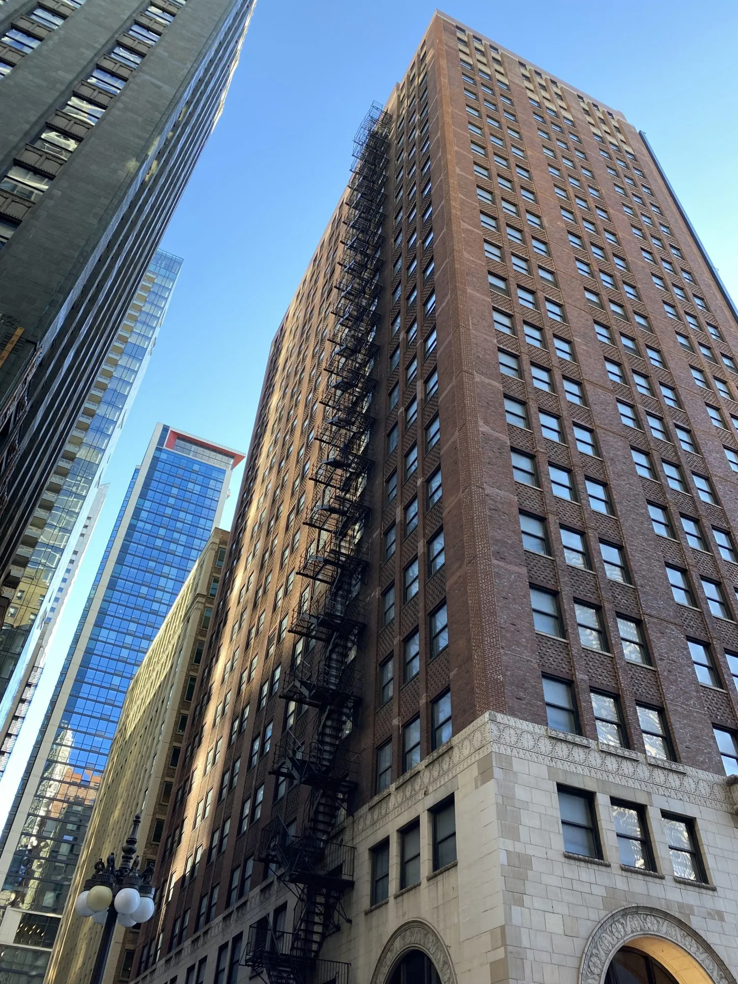 shot of tall, brick buildings from the street view pointed up. blue sky. Chicago
