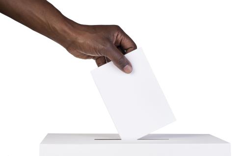 Hand placing a ballot in a ballot boxx