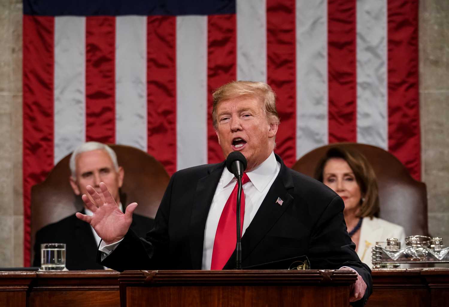 U.S. President Donald Trump speaking at the State of the Union with Vice President Mike Pence and Speaker of the House Nancy Pelosi behind him.