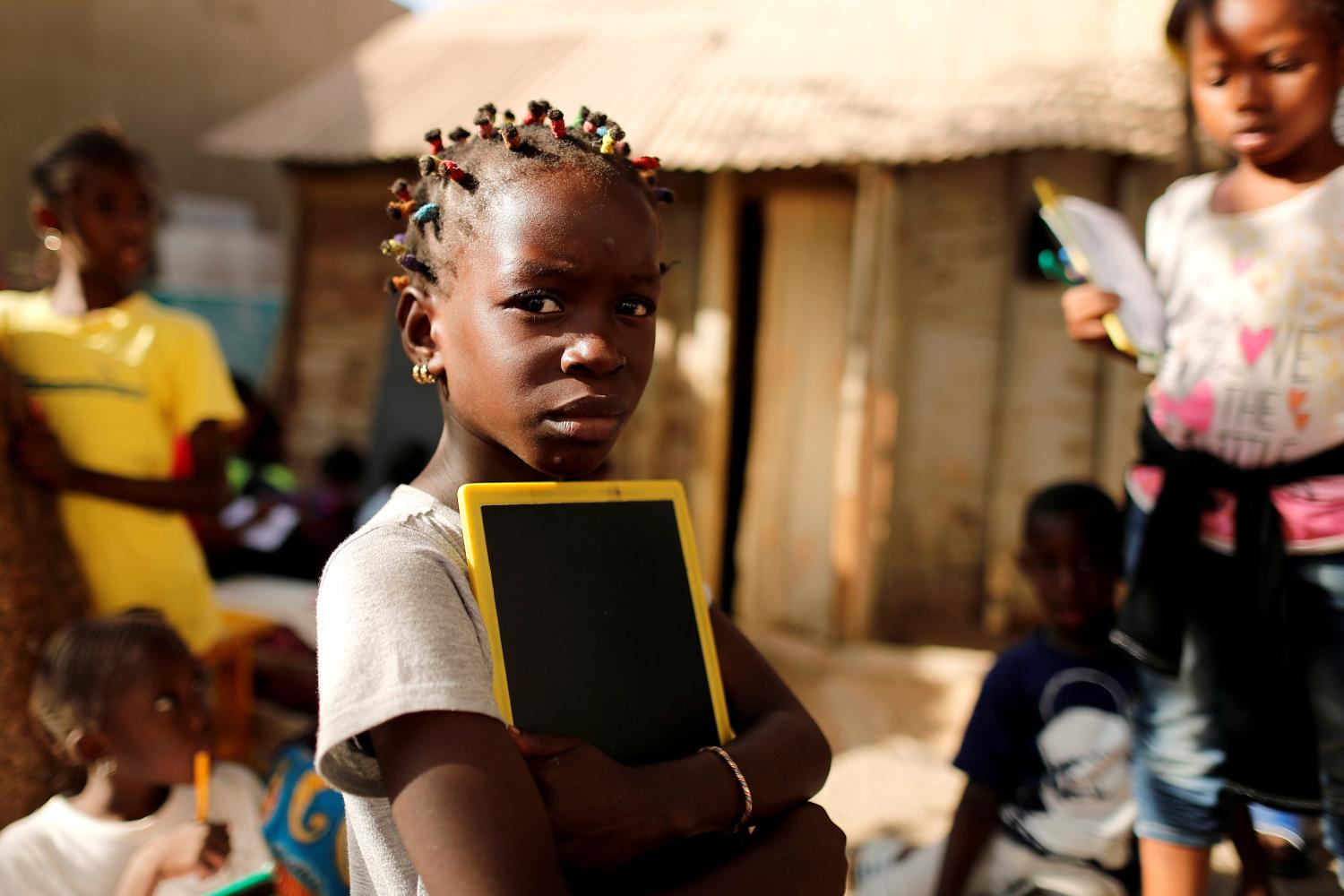 A girl holds her chalkboard as she arrives to attend lessons at the evening school in Ouakam neighbourhood, Dakar, Senegal January 16, 2019. Picture taken January 16, 2019. REUTERS/Zohra Bensemra