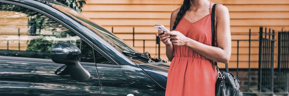 Car sharing rideshare mobile phone app woman using smartphone online to rent on travel holiday. Banner panorama. Technology device. Photo: Shutterstock