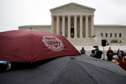 A person holds an umbrella with a Harvard logo print as demonstrators gather in support of affirmative action, as the U.S. Supreme Court is set to consider whether colleges may continue to use race as a factor in student admissions in two cases, at the U.S. Supreme Court building in Washington, U.S. October 31, 2022. REUTERS/Jonathan Ernst