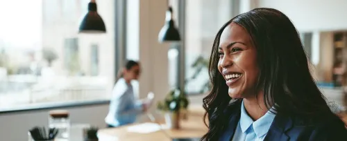 Young, Black business woman laughing while walking in an office