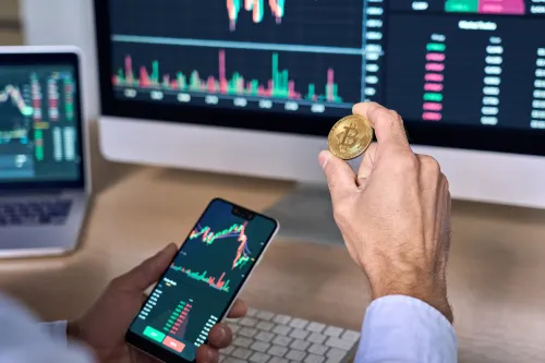 Business man crypto trader investor analyst holding smartphone and gold bitcoin coin buying cryptocurrency tokens analyzing stock market data investment risks using online trading mobile app concept.