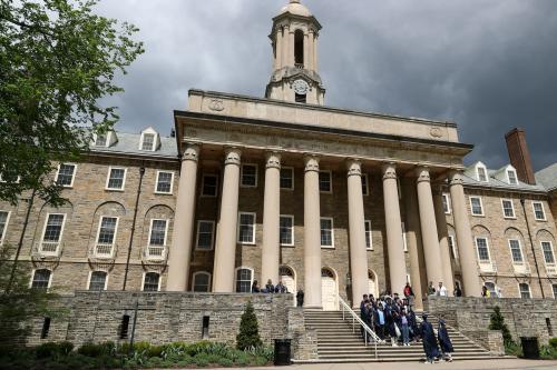 Students in caps and gowns pose for photos on the steps of Old Main on the campus of Penn State University in State College, Pa. on Sunday, April 23, 2023. Credit: Paul Weaver/Sipa USA)