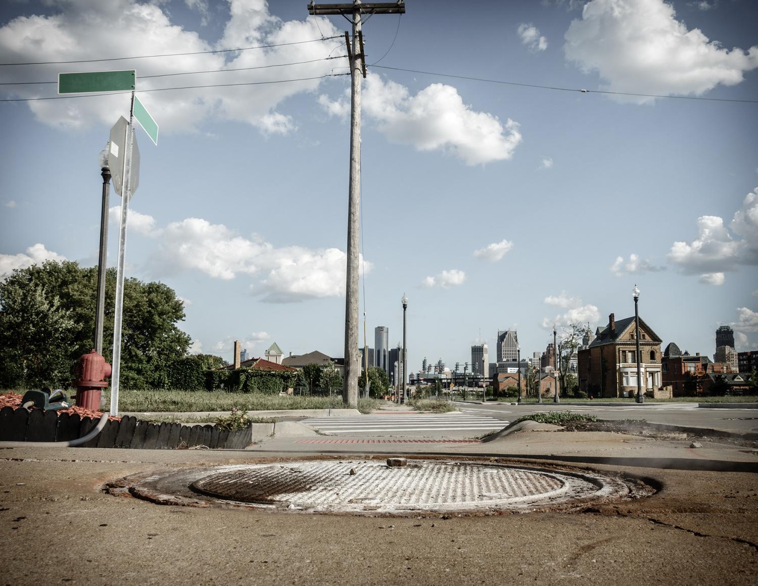 Distressed Detroit neihborhood with many abandoned houses. Downtown skyscrapers in the backdrop.