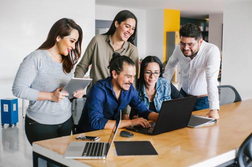 Group of Latin business people working together as a team while sitting at the office desk in a creative office