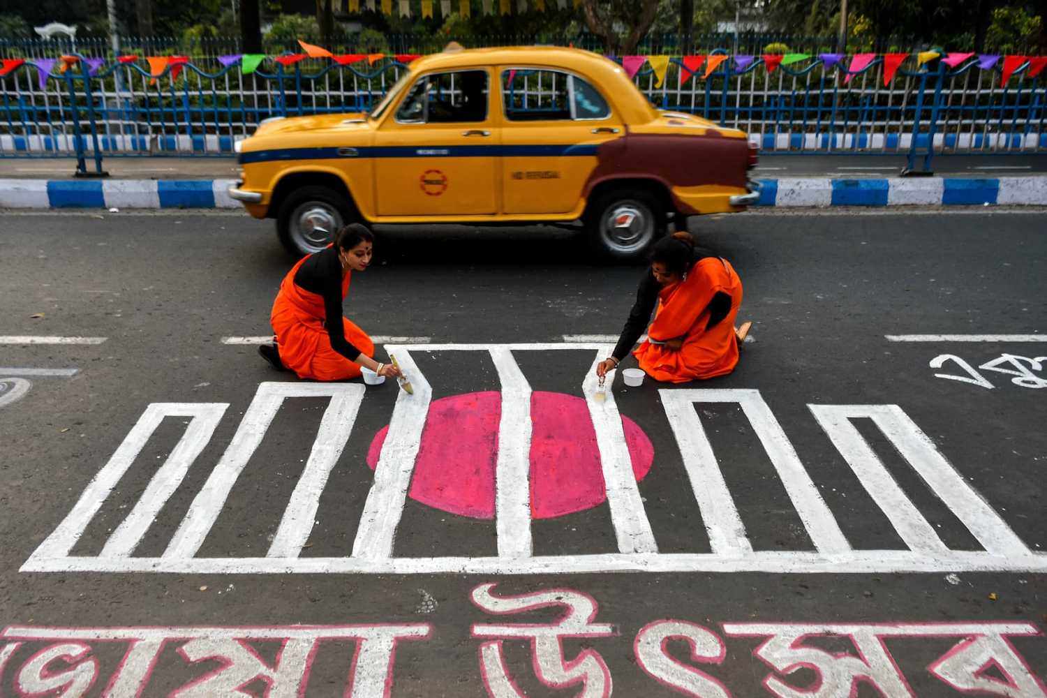 People are seen writing various messages in Bengali on a road to commemorate International Mother Language Day, a worldwide annual observance held to promote awareness of linguistic and cultural diversity, in Kolkata, India, on 20 February 2023.(Photo by Debarchan Chatterjee/NurPhoto)