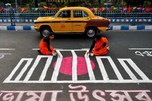 People are seen writing various messages in Bengali on a road to commemorate International Mother Language Day, a worldwide annual observance held to promote awareness of linguistic and cultural diversity, in Kolkata, India, on 20 February 2023.(Photo by Debarchan Chatterjee/NurPhoto)