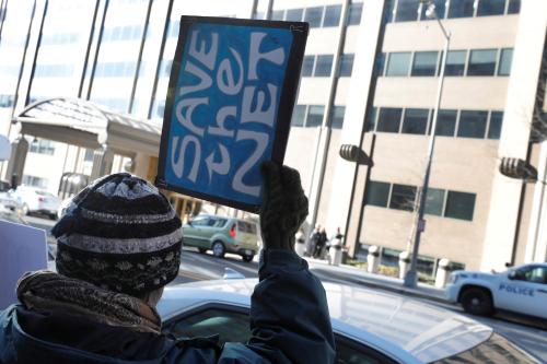 A net neutrality advocate holds a sign that reads "Save the Net" outside the Federal Communications Commission (FCC).