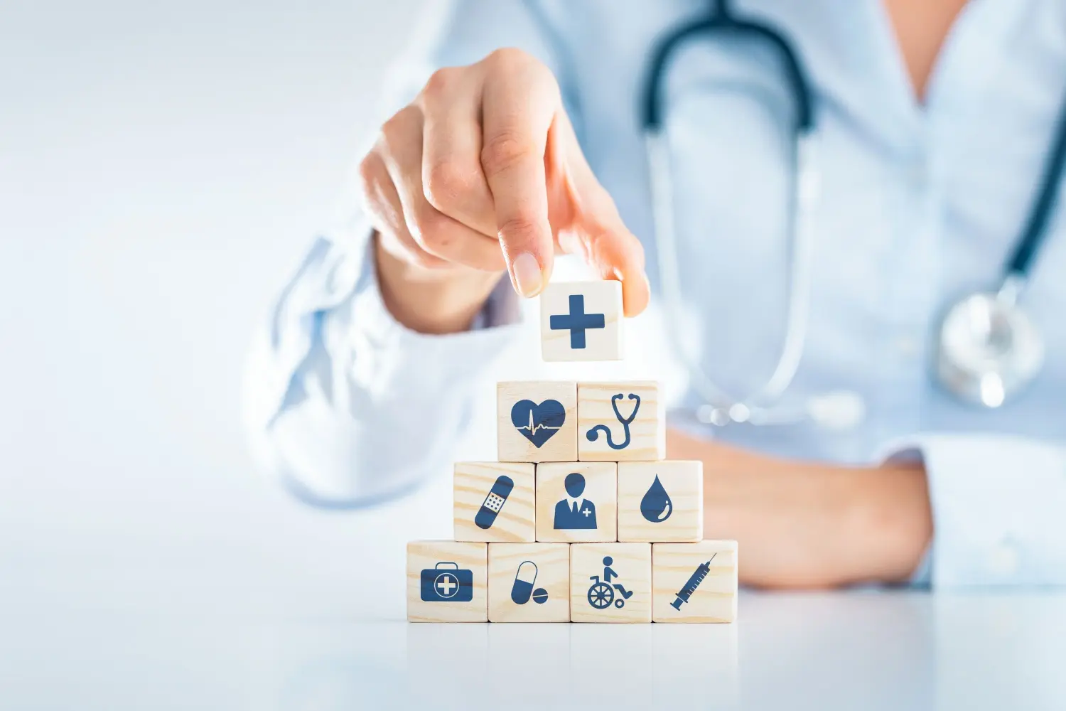 A medical professional stacks blocks representing parts of the health care system