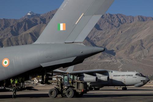 A military transport plane taxis as another unloads supplies at a forward airbase in Leh
