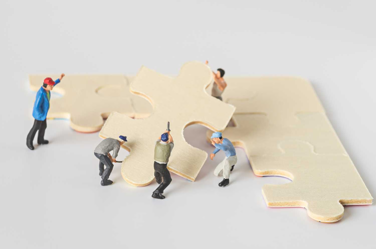 miniature worker team try to complete jigsaw puzzle