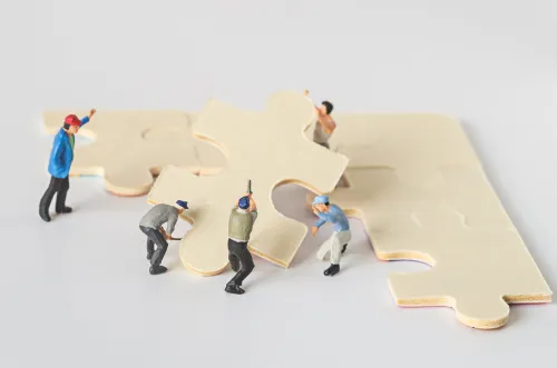 miniature worker team try to complete jigsaw puzzle