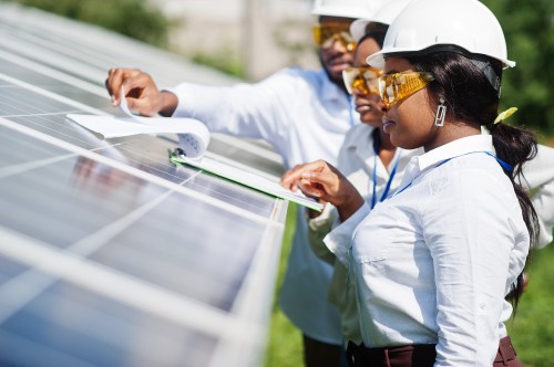 Solar panel technician checks the maintenance of the solar panels. Group of three black engineers meeting.