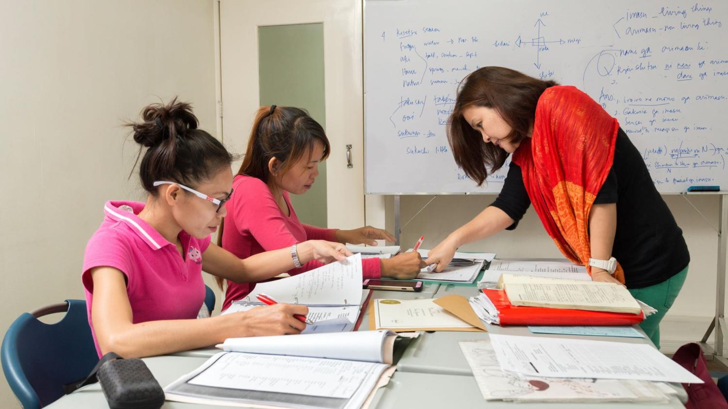 Manila, Philippines - A female teacher teaches two girls in the classroom at school.