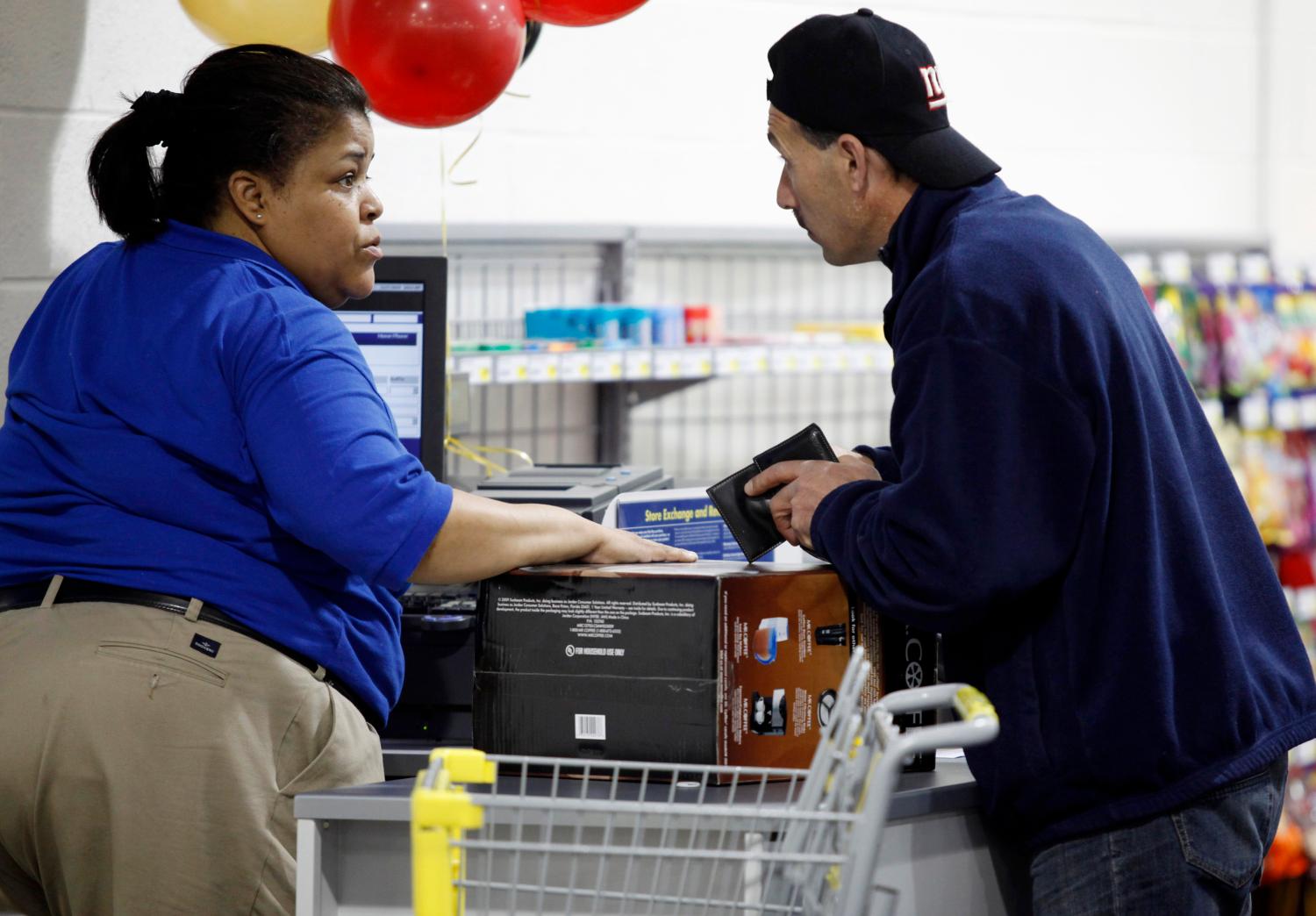 A man leans in to speak to a cashier while checking out at a Best Buy store in Flushing