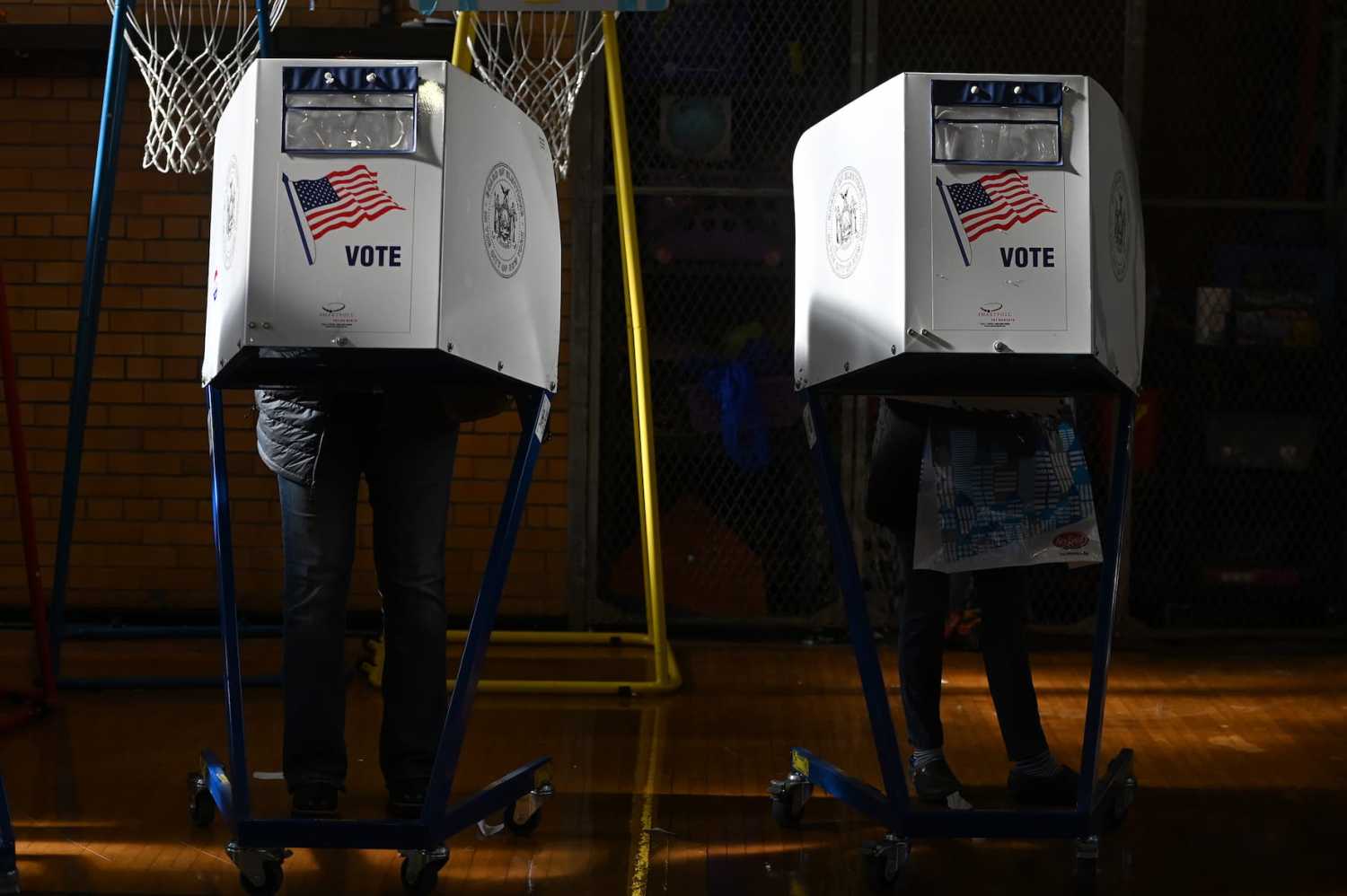 People stand behind a privacy booths to fill out their ballot before casting their votes for the 2022 midterm election, at P.S. 101 in the Queens borough of New York, NY, November 8, 2022.