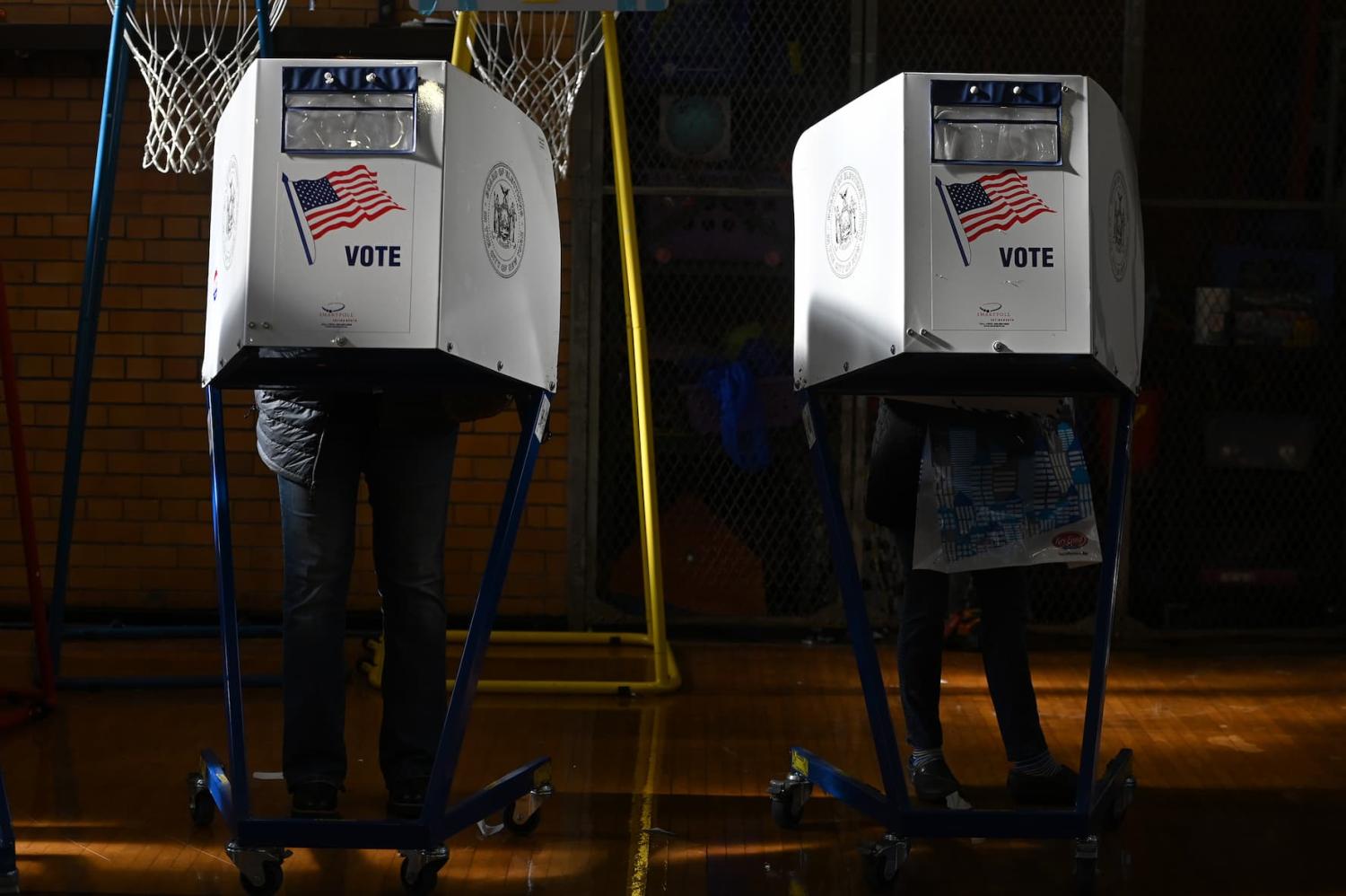 People stand behind a privacy booths to fill out their ballot before casting their votes for the 2022 midterm election, at P.S. 101 in the Queens borough of New York, NY, November 8, 2022.