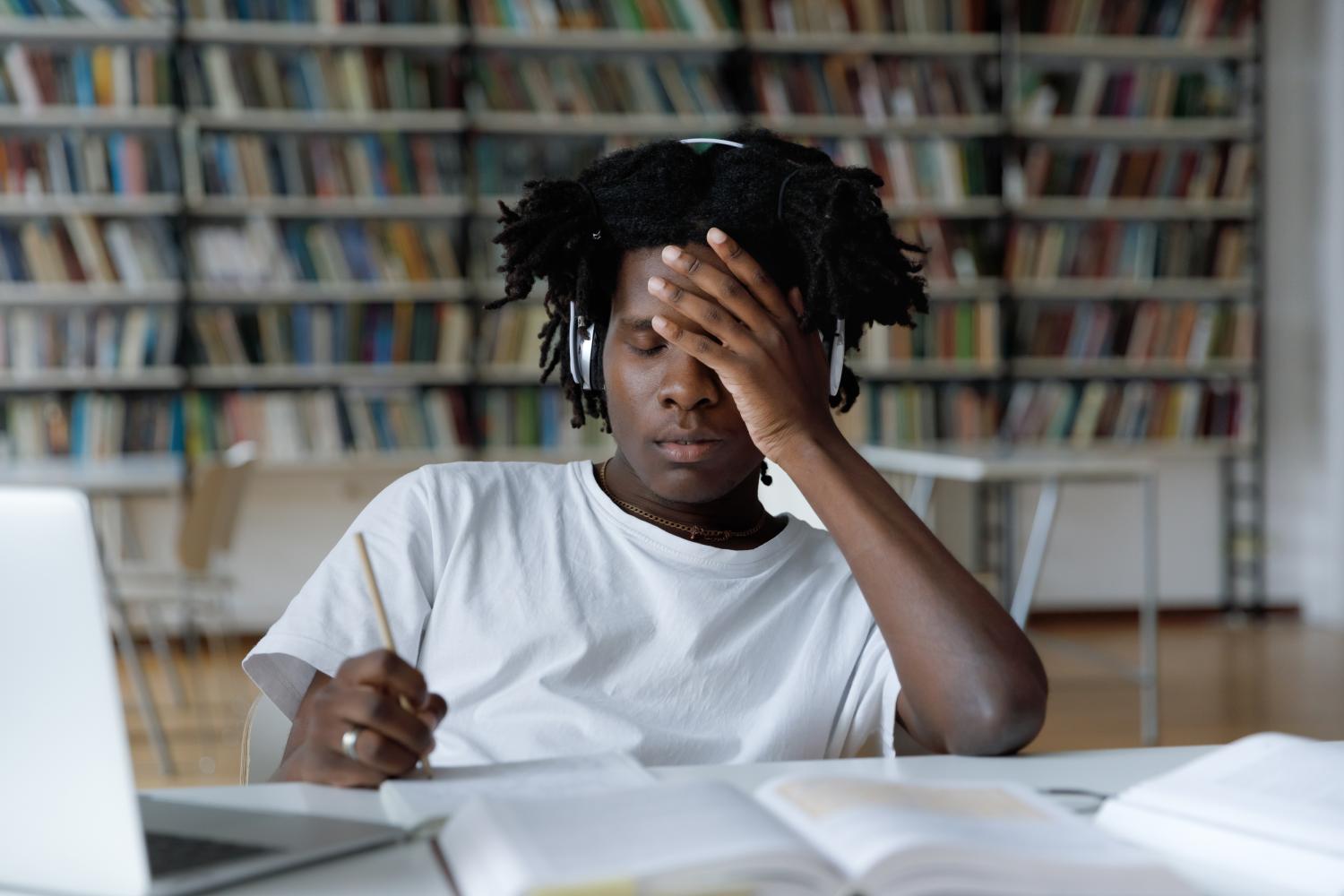 Black student suffers from headache while studying at the library.