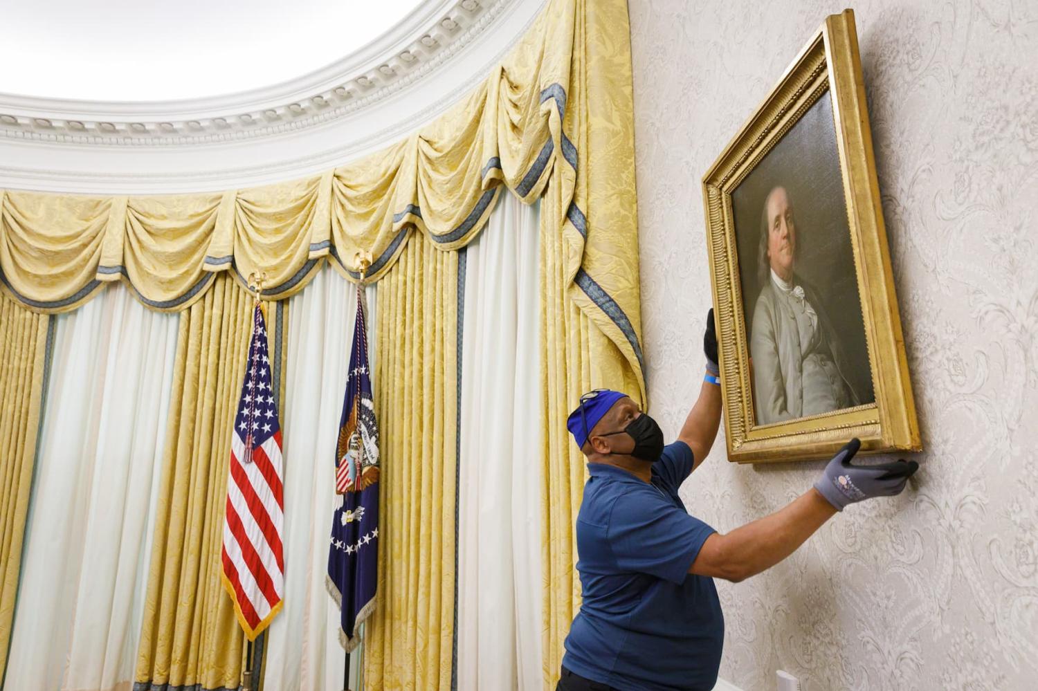 A member of the White House General Services staff hangs a painting of Benjamin Franklin in the Oval Office of the White House on Inauguration Day Wednesday, Jan. 20, 2021, transitioning the Oval Office in preparation for President Joe Biden's arrival. (Official White House Photo by Chandler West via Sipa USA)
