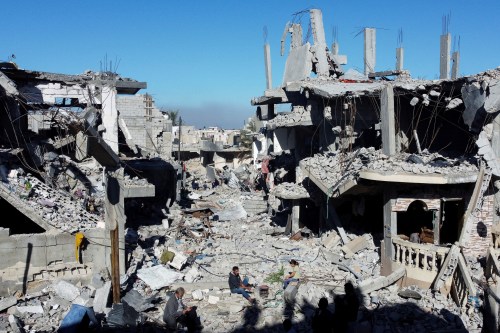 Palestinians cook among the houses destroyed in Israeli strikes during the conflict, amid the temporary truce between Israel and the Palestinian Islamist group Hamas, at Khan Younis refugee camp, in the southern Gaza Strip, November 29, 2023.