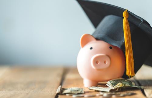Piggy bank with graduation cap on a pile of money.
