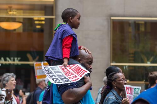 New York, USA - 21 September 2014: Young boy is carried through crowds of people marching and campaigning for greater environmental awareness during the Peoples Climate March through New York City