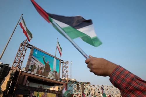 A man waves a Palestinian flag next to a portrait of former commander of the Islamic Revolutionary Guard Corps, General Qasem Soleimani, before Hezbollah's Secretary-General, Hassan Nasrallah, gives a speech, in Tehran on November 3, 2023.