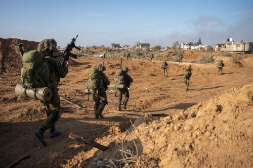 Israeli soldiers walking in a line in a field in Gaza