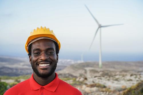 Black engineer man working on a windmill farm - Focus on face