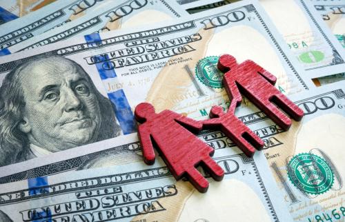 Wooden figures of a family on a pile of $100 dollar bills