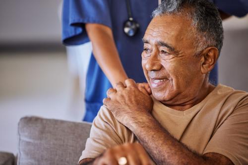 Senior citizen clasping the hand of a healthcare worker