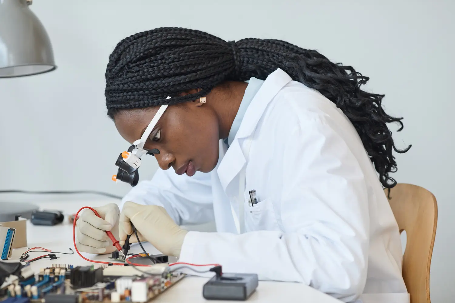 Side view portrait of black female engineer inspecting electronic parts in laboratory