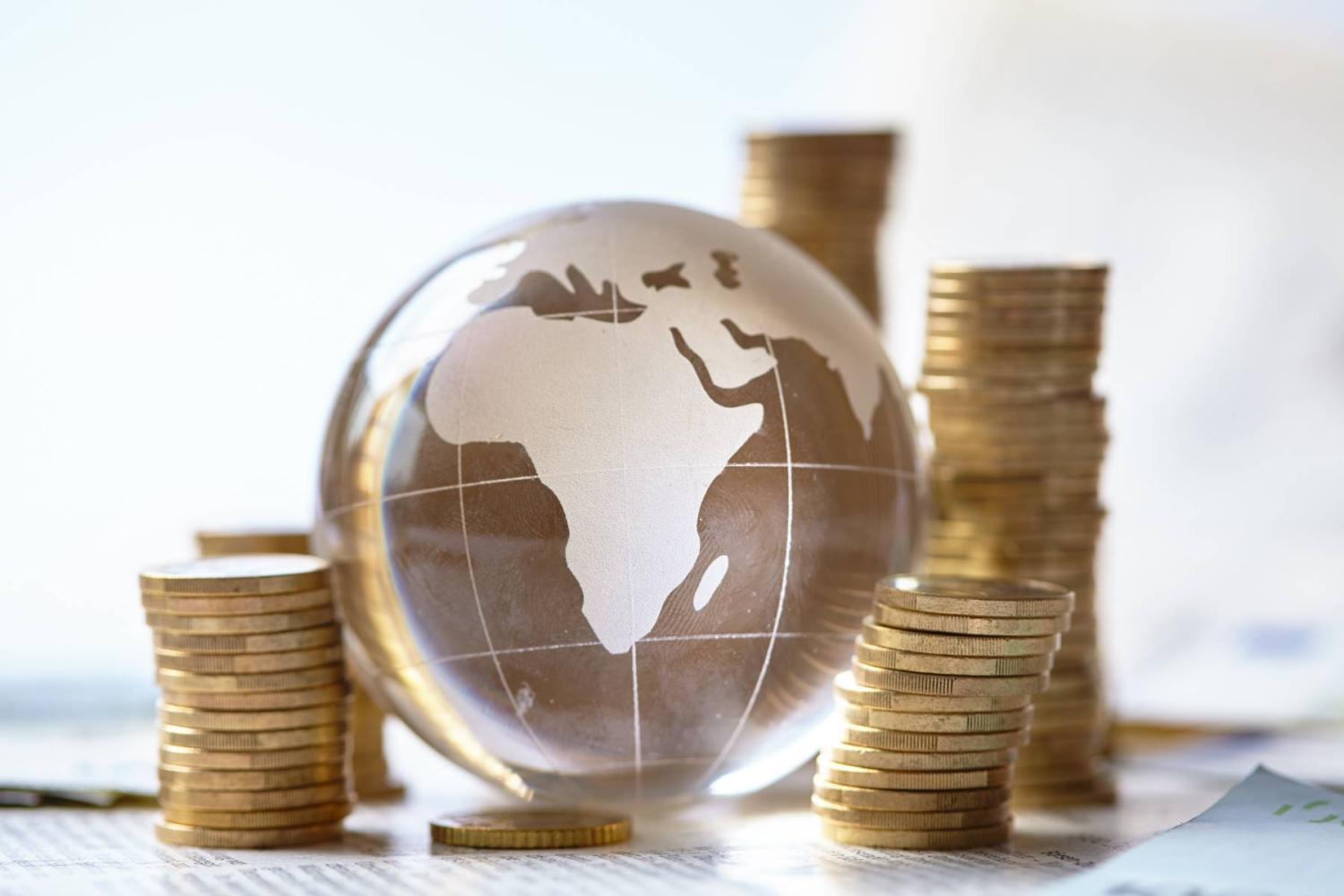 Coins piled around a globe featuring Africa (Photo credit: allstars / Shutterstock)
