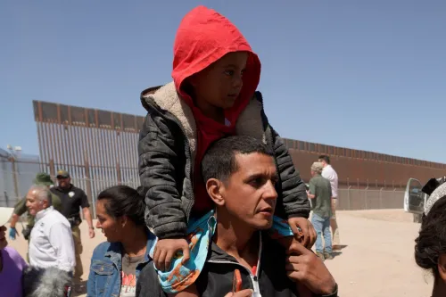 A father carrying his son on his shoulders at the US/Mexico border