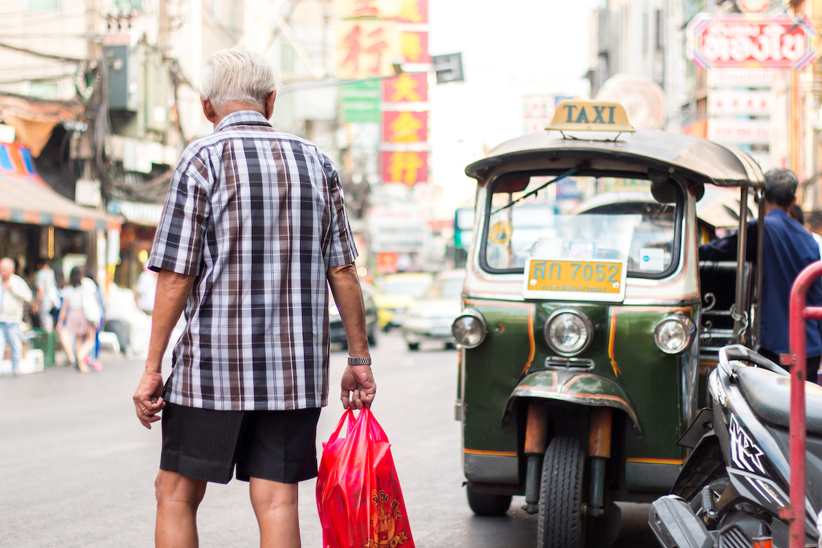 BANGKOK, THAILAND - JANUARY 1 2017: Tourists visit Yaowarat in Thailand. Traffic in Chinatown, Bangkok. Older people stand by waiting for public buses. Photo credit: Shutterstock