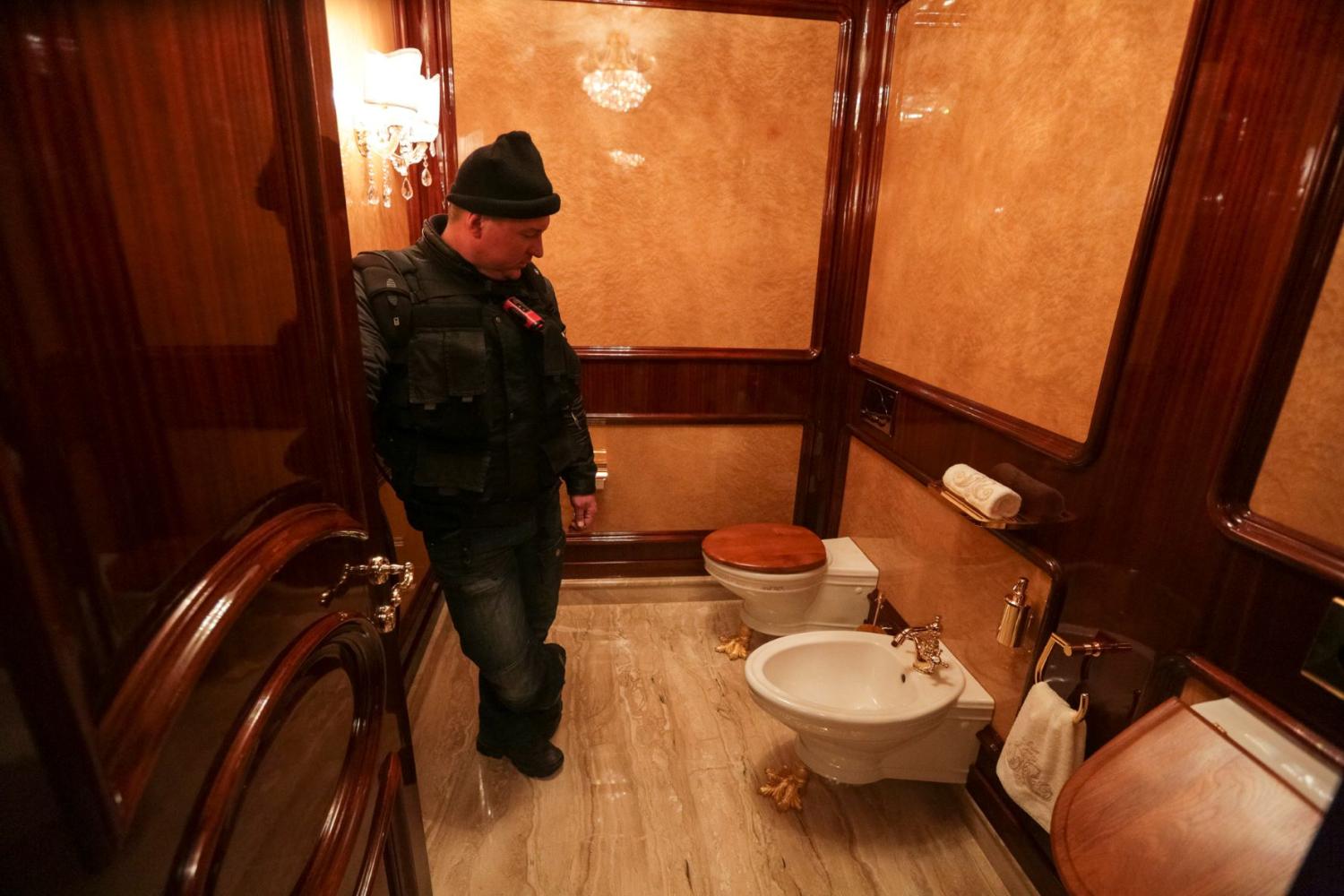 A man stands inside a lavatory as anti-government protesters and journalists walk on the grounds of the Mezhyhirya residence of Ukraine's President Viktor Yanukovych in the village Novi Petrivtsi, outside Kyiv February 22, 2014.
