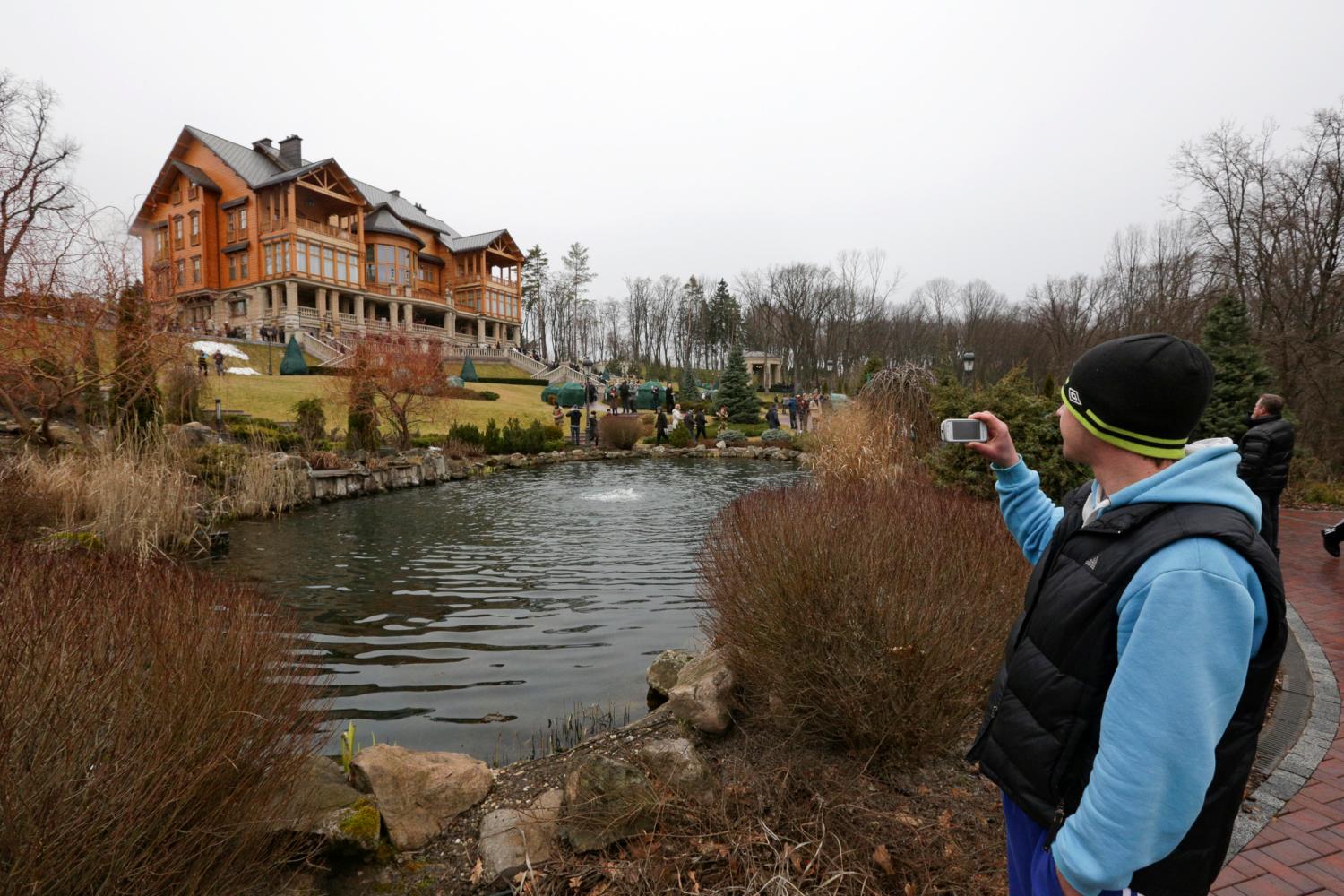 A man takes pictures as anti-government protesters and journalists walk on the grounds of the Mezhyhirya residence of Ukraine's President Yanukovych in the village Novi Petrivtsi, outside Kyiv, February 22, 2014.