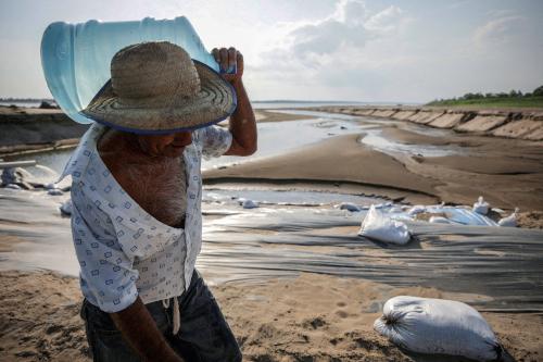 A man carries a water jug during a historic drought in the Amazon at the dry riverbed of the Paraua river in Careiro da Varzea, Amazonas state, Brazil October 26, 2023. REUTERS/Bruno Kelly