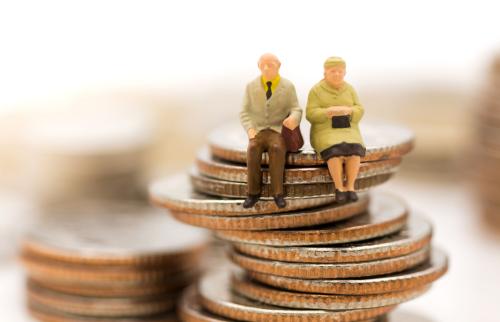 Miniature figures of seniors sitting on a stack of coins.