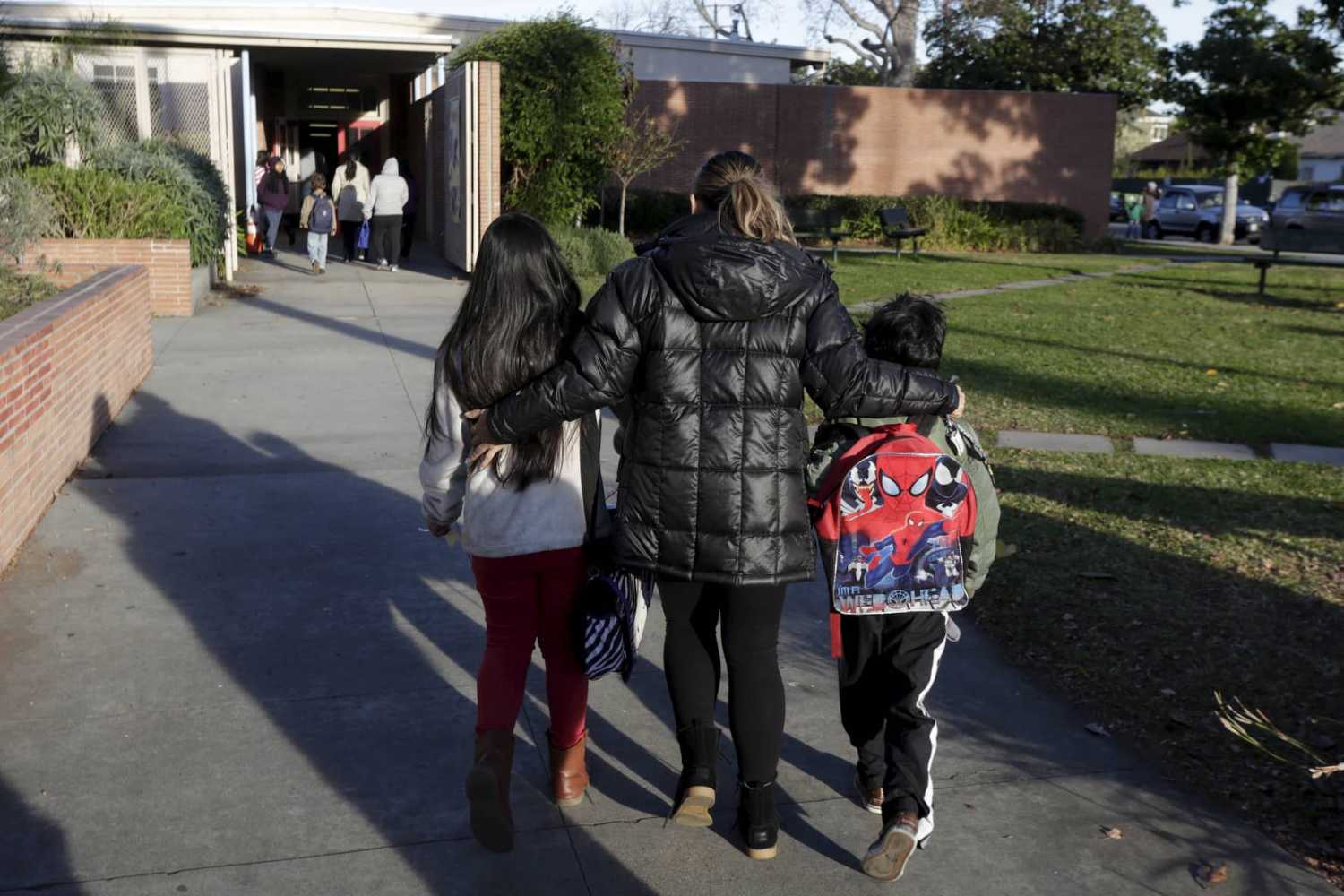 A mother escorts her children on to the campus of Beethoven Street Elementary School in Los Angeles, California on December 16, 2015.