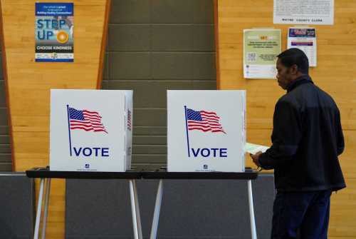 A man goes behind a voting booth as Democrats and Republicans hold their Michigan primary presidential election, in Detroit, Michigan, U.S. February 27, 2024.