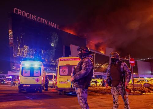 Law enforcement officers stand guard near the burning Crocus City Hall concert venue following a shooting incident, outside Moscow, Russia, March 22, 2024.