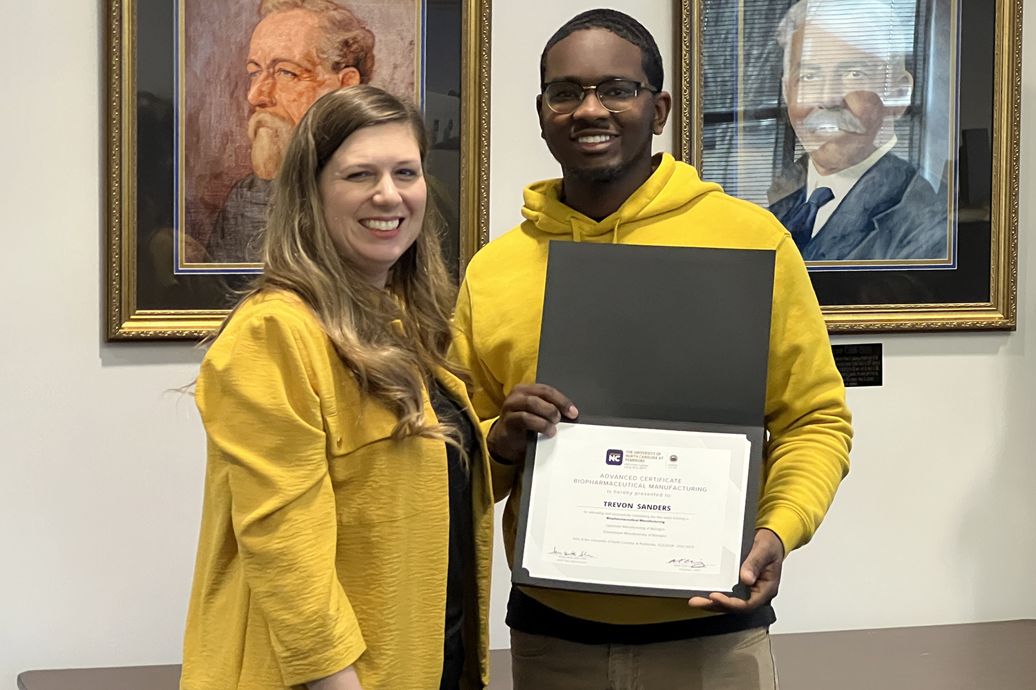 Graduate of the first HBCU/HAIU cohort hosted by UNC Pembroke, a graduate with the Associate Dean of the College of Arts and Sciences, Ashley Allen on their certificate day. “Trevon Sanders receives his Advanced Certificate in Biopharmaceutical Manufacturing after completing the two-week training provided at UNC Pembroke”. (Credit: UNCP)