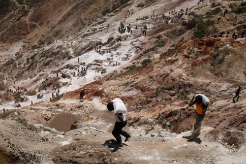 Laborers carry sacks of ore.