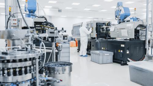 On a Factory Scientist in Sterile Protective Clothing Work on a Modern Industrial 3D Printing Machinery. Biotechnological and Semiconductor Manufacturing Process Shot from Inside.