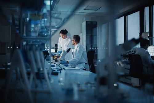 Lab scientists look through a microscope