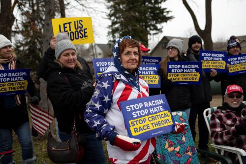 Supporters hold posters regarding critical race theory as people gather to attend a "Let's Go Brandon Festival" rally, promoted by the Michigan Conservative Coalition and in opposition to U.S. President Joe Biden, in the Brandon Township village of Ortonville, Michigan, U.S., November 20, 2021.